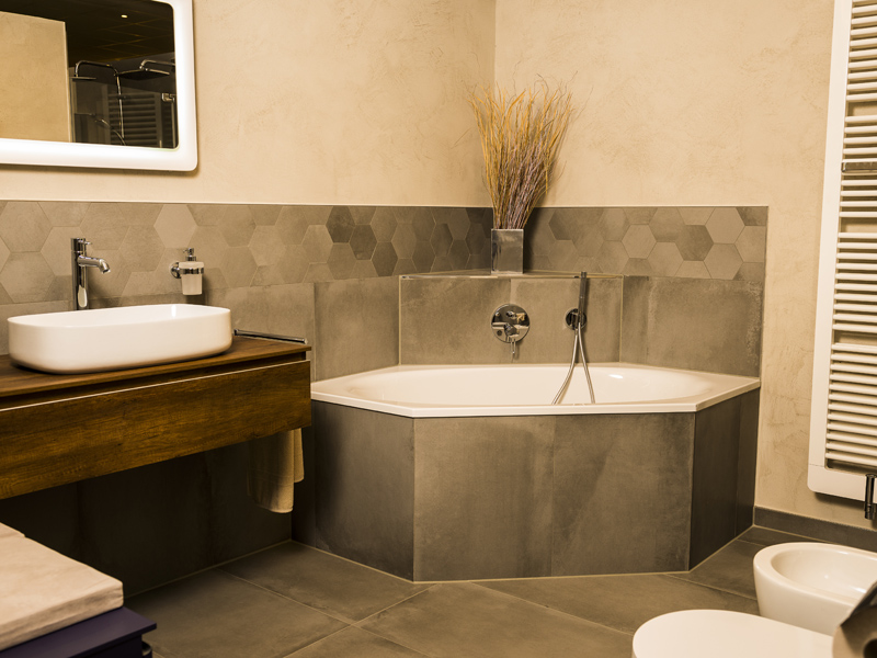 Modernes Badezimmer mit Eckbadewanne – hochwertige Badgestaltung und Komfort Modern gestaltetes Badezimmer mit Eckbadewanne, Waschtisch und stilvollen Fliesen für ein komfortables Wohnambiente
